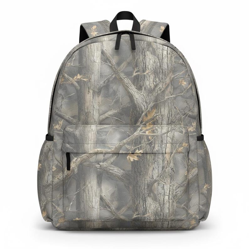 May include: A gray and brown camouflage backpack with a front pocket and black zippers. The backpack features a top handle and adjustable shoulder straps. The pattern resembles a forest scene with tree trunks and branches.