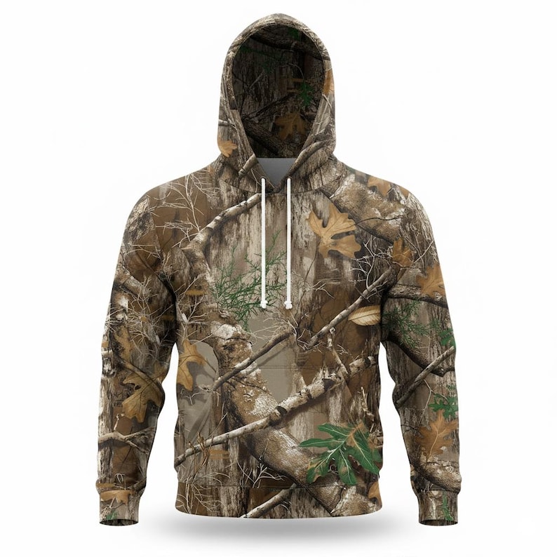 May include: A hooded sweatshirt with a camouflage pattern in shades of brown, green, and tan. The hoodie features a drawstring and a front pocket. The design incorporates images of branches, leaves, and bark.