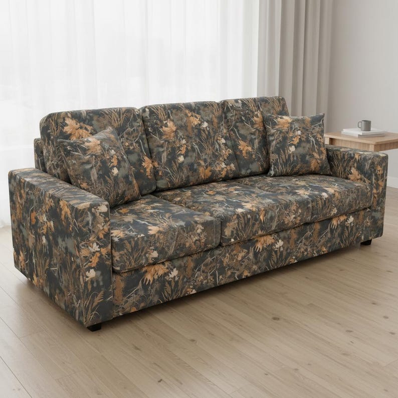 May include: A three-cushion sofa with a camouflage pattern in shades of brown, green, and gray. The sofa includes two matching throw pillows. The fabric features a leaf and foliage design, creating a natural, outdoorsy aesthetic.