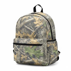 Puede incluir: Una mochila de camuflaje con cremallera negra, asa y bolsillo lateral de malla. La mochila presenta un patr&oacute;n de corteza de &aacute;rbol marr&oacute;n y hojas, con una hoja verde visible en el bolsillo delantero.