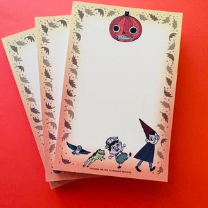 May include: Three rectangular sheets of cream-colored stationery paper featuring a border of brown leaves. The top center displays a red pumpkin with a black cat, while the bottom shows a blue bird, a green frog, and two cartoon characters.