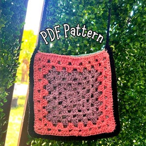 Puede incluir: Un bolso cuadrado de ganchillo con un diseño de granny square. El bolso presenta un degradado de color de rosa a morado, con un borde y una correa negros. El texto "PDF Pattern" se muestra en la parte superior. El bolso cuelga sobre un fondo verde frondoso.