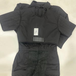 May include: Black protective fencing suit, including a jacket and pants. The jacket has quilted shoulder pads and short sleeves. The pants have reinforced knee patches and pockets. The suit has a label that reads "GWABO".