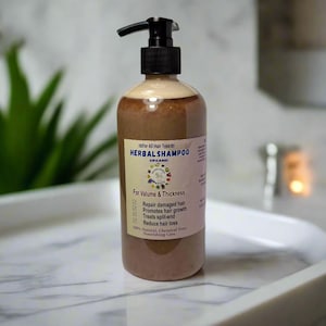 May include: A brown herbal shampoo bottle with a black pump dispenser. The label reads "HERBAL SHAMPOO" and lists benefits like repairing damaged hair and reducing hair loss. The bottle is on a white tray.