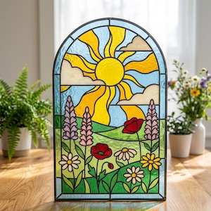 May include: An arched stained glass panel featuring a bright yellow sun with radiating rays against a light blue sky with beige clouds. The foreground depicts a green meadow filled with purple lupines, red poppies, and white and yellow daisies.