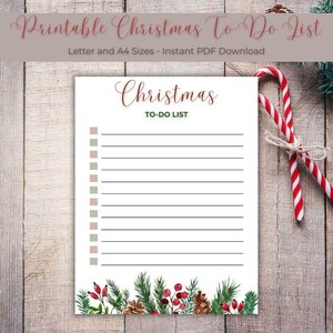 Może przedstawiać: Biała świąteczna lista rzeczy do zrobienia z tytułem "Christmas TO-DO LIST" w zielonym i czerwonym skrypcie. Lista ma dekoracyjną obwódkę z igieł sosnowych, jagód i szyszek. Dwie czerwono-białe laski cukrowe są związane sznurkiem.