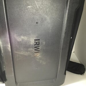 May include: A black, rectangular tool bag with the brand name "IRWIN" printed in silver. The bag has a textured surface and a black strap. The image is taken from a low angle.