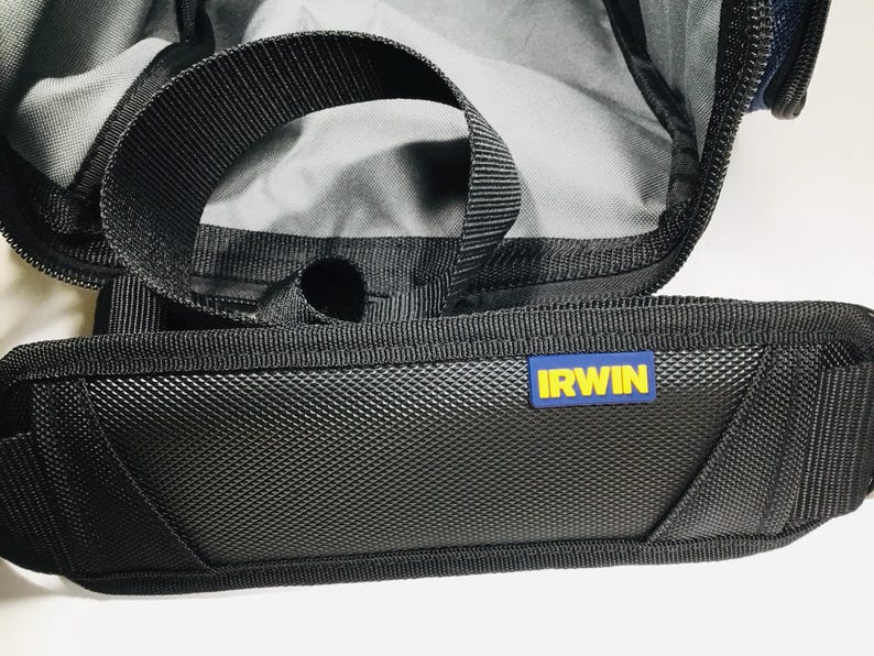 May include: Close-up of a black tool bag with a textured front panel and a black handle. The bag has a blue and yellow "IRWIN" logo. The interior of the bag is visible, with a gray lining.