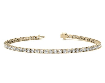 May include: A gold tennis bracelet with a row of round-cut diamonds. The bracelet is set on a gold band and has a clasp closure. The diamonds are clear and sparkling, and the bracelet is displayed on a white background.