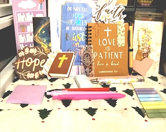 May include: A collection of inspirational stationery items, including notebooks, bookmarks, and decorative signs. The items feature religious quotes and symbols, such as crosses and the word "faith." Pens and sticky notes are also visible.