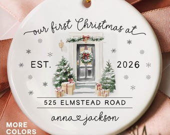 May include: A round white ceramic ornament featuring a watercolor illustration of a front door with a wreath, two Christmas trees, and wrapped gifts. The text reads: our first Christmas at EST. 2026 525 ELMSTEAD ROAD anna & jackson.