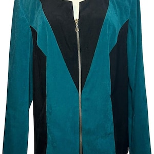 May include: Teal and black zip-up jacket. The jacket features a teal body with black panels in a V-shape down the front. It has a round neckline and a silver zipper. The jacket is displayed on a mannequin.