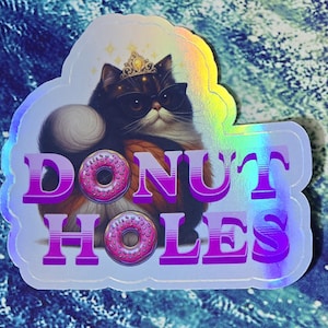 May include: Holographic sticker featuring a cat wearing sunglasses and a crown, with the words "DONUT HOLES" in purple. The cat has a fluffy tail and is surrounded by a light blue outline. Two pink donuts are also featured.