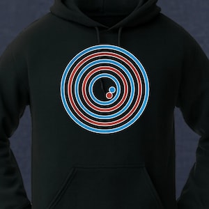 May include: A black hooded sweatshirt featuring a large graphic on the chest. The design consists of multiple concentric circles in alternating red and light blue colors. Inside the center circle, there are two small, solid circles in red and blue.