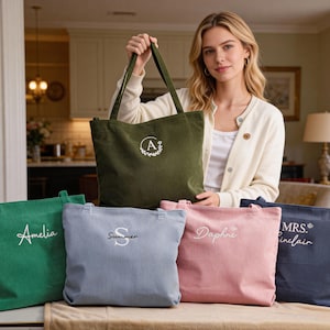 May include: A collection of corduroy tote bags in various colors, including green, blue, pink, and navy. Each bag features personalized embroidery with names or initials. One bag is held by a person.