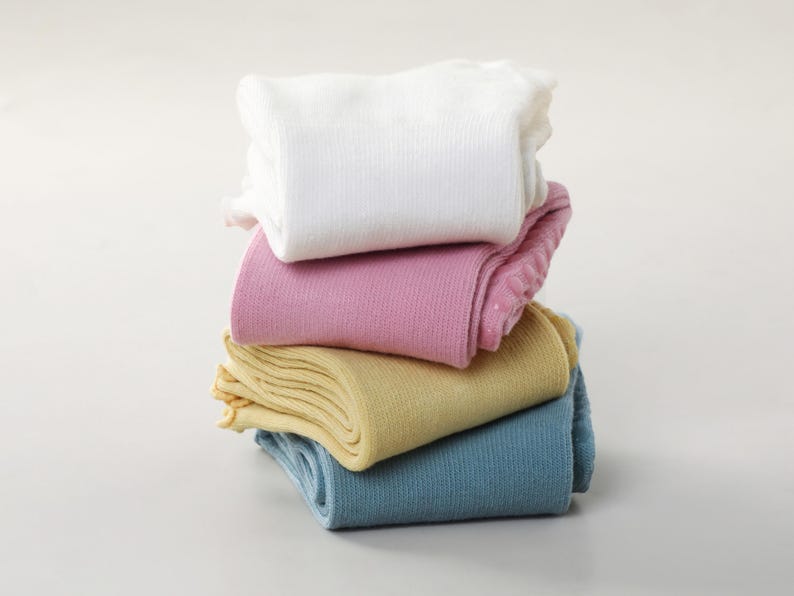 May include: A stack of folded socks in various pastel colors: white, pink, yellow, and blue. The socks are neatly arranged, showcasing their soft texture and ribbed design. The image is set against a plain white background.