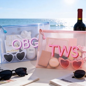 May include: Two mesh zipper pouches, one blue and one pink, each with a personalized initial design. The blue pouch has the letters "OBG" and the pink pouch has "TWS". Sunglasses and wine bottles are also visible.