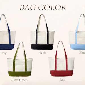 May include: Five canvas tote bags with two shoulder straps and a front pocket, displayed in a grid. The bags feature a cream-colored upper section and a solid-colored base and straps in navy, black, light blue, olive green, and red. Text reads BAG COLOR.