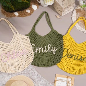 May include: Three crocheted tote bags in cream, olive green, and yellow. Each bag has a name embroidered on it: "Chloe", "Emily", and "Denise". The bags are open-weave and have long handles.