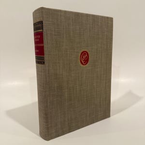 May include: A hardcover book with a tan linen cover. The spine is red with gold lettering that reads "Selected Works" and "The Book Club". A red emblem is centered on the front cover.