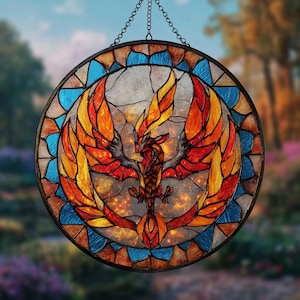 May include: Round stained glass window featuring a phoenix with outstretched wings. The phoenix is depicted in shades of red, orange, and yellow, set against a background of blue and brown glass. The window is framed with a black metal border and suspended by a chain.