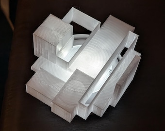 May include: A white, geometric 3D-printed lamp with a complex, layered design. The lamp has a cube-like structure with rectangular and angled elements. The interior glows with a soft light, creating a modern and artistic aesthetic.