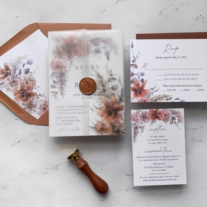 Könnte beinhalten: Hochzeits-Einladungssuite mit einem Aquarell-Blumenmuster in Braun-, Rosa- und Blautönen. Die Einladung enthält die Namen des Paares, das Hochzeitsdatum und den Veranstaltungsort. Die RSVP-Karte enthält eine Antwortfrist und Optionen zum Annehmen oder Ablehnen der Einladung. Die Empfangs-Karte enthält den Empfangs-Ort, die Uhrzeit und die Wegbeschreibung.