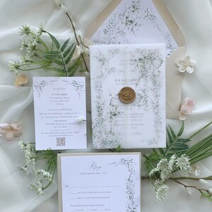 May include: A wedding invitation suite with a floral design. The invitation features a watercolor illustration of delicate white flowers and greenery. The RSVP card has a floral border and a space for guests to indicate their attendance. The text on the invitation reads "Penelope & Michael Smith" and the text on the RSVP card reads "RSVP kindly requested by May 1, 2023".