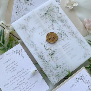 May include: Wedding invitation suite with a watercolor floral design. The invitation is on a white background with a translucent overlay with a floral pattern. The invitation includes the names Penelope and Michele Smith, the date June 5th, and the location The Abbey. The RSVP card is on a white background with a floral design and the text "RSVP" and "Kindly respond by May 1, 2025".