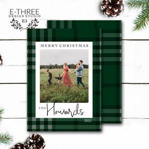 May include: A green and white plaid Christmas card with a photo of a family of four in a field. The text "Merry Christmas" is at the top of the card, and the text "The Howards 2021" is at the bottom.