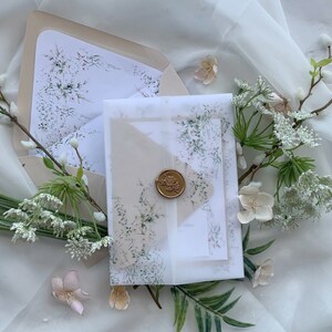 May include: A set of two wedding invitations with a delicate floral design. The invitations are on a white background with a light brown envelope. The envelope has a wax seal with a floral design.
