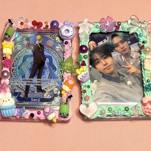 May include: Two rectangular plastic card holders decorated with colorful resin charms. The left holder is pink and features a Sanji character card, while the right holder is mint green and displays a photograph of two individuals posing together.