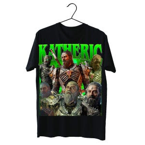 Puede incluir: Camiseta negra con un diseño gráfico que presenta la palabra "KATHERIC" en letras grandes de color verde neón. El diseño incluye múltiples imágenes de un guerrero barbudo con armadura y una espada, sobre un fondo verde.