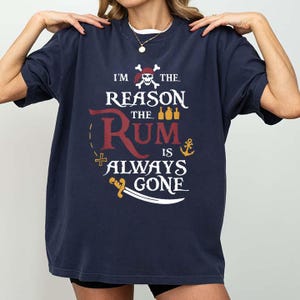 Op de afbeelding: Marineblauw T-shirt met de tekst "I'm the reason the rum is always gone". Het ontwerp bevat een schedel en gekruiste botten, flessen, een anker en een zwaard. Een casual kledingstuk.
