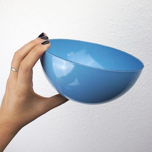 Puede incluir: Un cuenco de cerámica azul claro sostenido en una mano. El cuenco es redondo y tiene un acabado liso y brillante.
