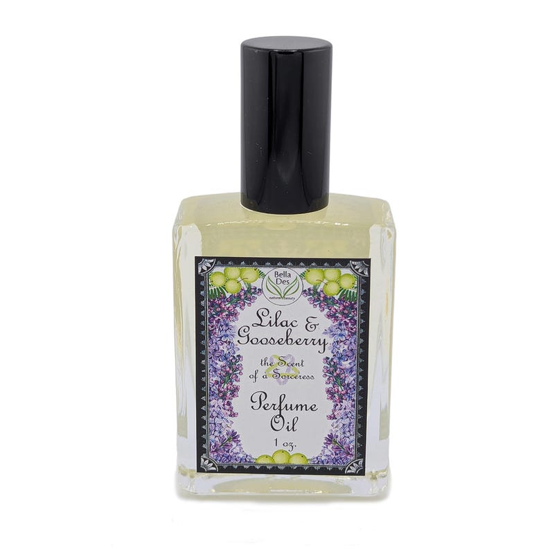 Op de afbeelding: Een heldere glazen parfumolie fles met een zwarte dop. Het etiket leest "Lilac & Gooseberry" met bloemen- en fruitillustraties. De fles bevat 30 ml parfumolie.