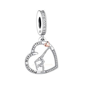 Può includere: Ciondolo in argento a forma di cuore con una silhouette di ginnasta all'interno. Il cuore ha le parole "Practice Makes Perfect" incise intorno. Il ciondolo ha un piccolo cuore rosso in cima.