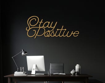 Letrero de pared metálico "Mantén una actitud positiva", estilo moderno con letras cursivas.