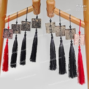 Puede incluir: Colgantes cuadrados decorativos con diseños intrincados y largas borlas negras. Algunos colgantes tienen caracteres chinos. Los colgantes están suspendidos de una estructura de madera, con borlas rojas en los extremos.