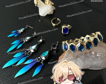 May include: An assortment of jewelry including earrings, rings, and a bracelet. The earrings feature blue and silver accents. The rings are gold with a blue gemstone. The bracelet has gold and blue hexagonal gems. A character sticker is also present.