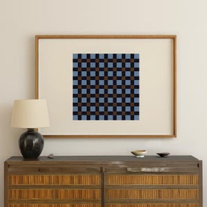Puede incluir: Obra de arte enmarcada con un patrón geométrico de cuadrados alternos. El diseño incorpora cuadrados azul marino, azul claro y marrón, creando una composición en forma de cuadrícula. La obra de arte se exhibe en un marco de madera.