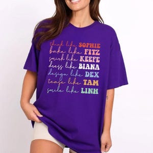 Puede incluir: Una camiseta morada con texto colorido. El texto dice: "think like SOPHIE, bake like FITZ, smirk like KEEFE, dress like BIANA, design like DEX, tease like TAM, smile like LINH."