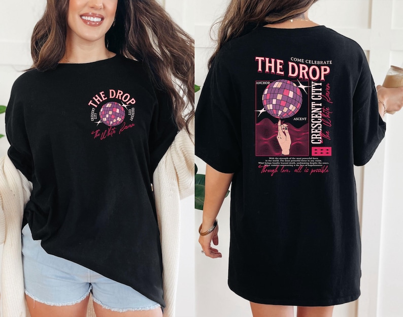 May include: Black t-shirt with a graphic design featuring a disco ball and the text "THE DROP". The design includes the words "Crescent City" and "The White Haven". The shirt has a relaxed fit.
