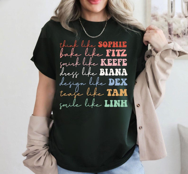 Puede incluir: Camiseta verde oscuro con texto colorido. La camiseta presenta las frases "think like SOPHIE", "bake like FITZ", "smirk like KEEFE", "dress like BIANA", "design like DEX", "tease like TAM" y "smile like LINH".