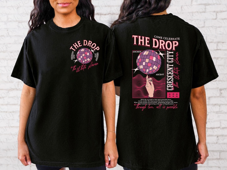 May include: Black t-shirt with a front and back graphic design. The front features a disco ball graphic with the text "THE DROP" and "The White Raven". The back has a disco ball graphic, text "THE DROP", "CRESCENT CITY", and "through love, all is possible."