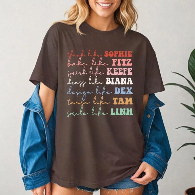 Puede incluir: Una camiseta marr&oacute;n con texto colorido que dice "think like SOPHIE, bake like FITZ, smirk like KEEFE, dress like BIANA, design like DEX, tease like TAM, smile like LINH." La camiseta es de estilo casual.