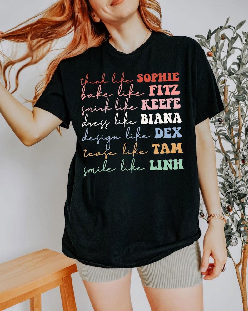 Puede incluir: Camiseta negra con texto colorido: "think like SOPHIE, bake like FITZ, smirk like KEEFE, dress like BIANA, design like DEX, tease like TAM, smile like LINH." El texto es multicolor y con diferentes fuentes.