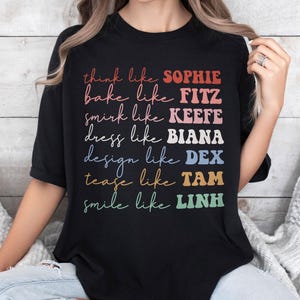 Puede incluir: Camiseta negra con texto colorido que dice "think like SOPHIE, bake like FITZ, smirk like KEEFE, dress like BIANA, design like DEX, tease like TAM, smile like LINH". El texto est&aacute; en varios colores y fuentes.