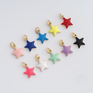 Könnte beinhalten: Eine Sammlung farbenfroher sternförmiger Anhänger mit goldfarbenen Schlaufen. Die Anhänger sind in verschiedenen Farben erhältlich, darunter Rosa, Blau, Gelb, Rot, Schwarz, Weiß, Grün und Lila. Geeignet für Schmuckherstellung oder Bastelprojekte.