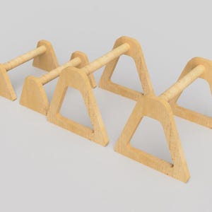 May include: Four wooden parallettes in a light wood color. Each parallette has a rectangular base, a triangular support, and a cylindrical handle. The parallettes are arranged in a row, with the handles parallel to each other.